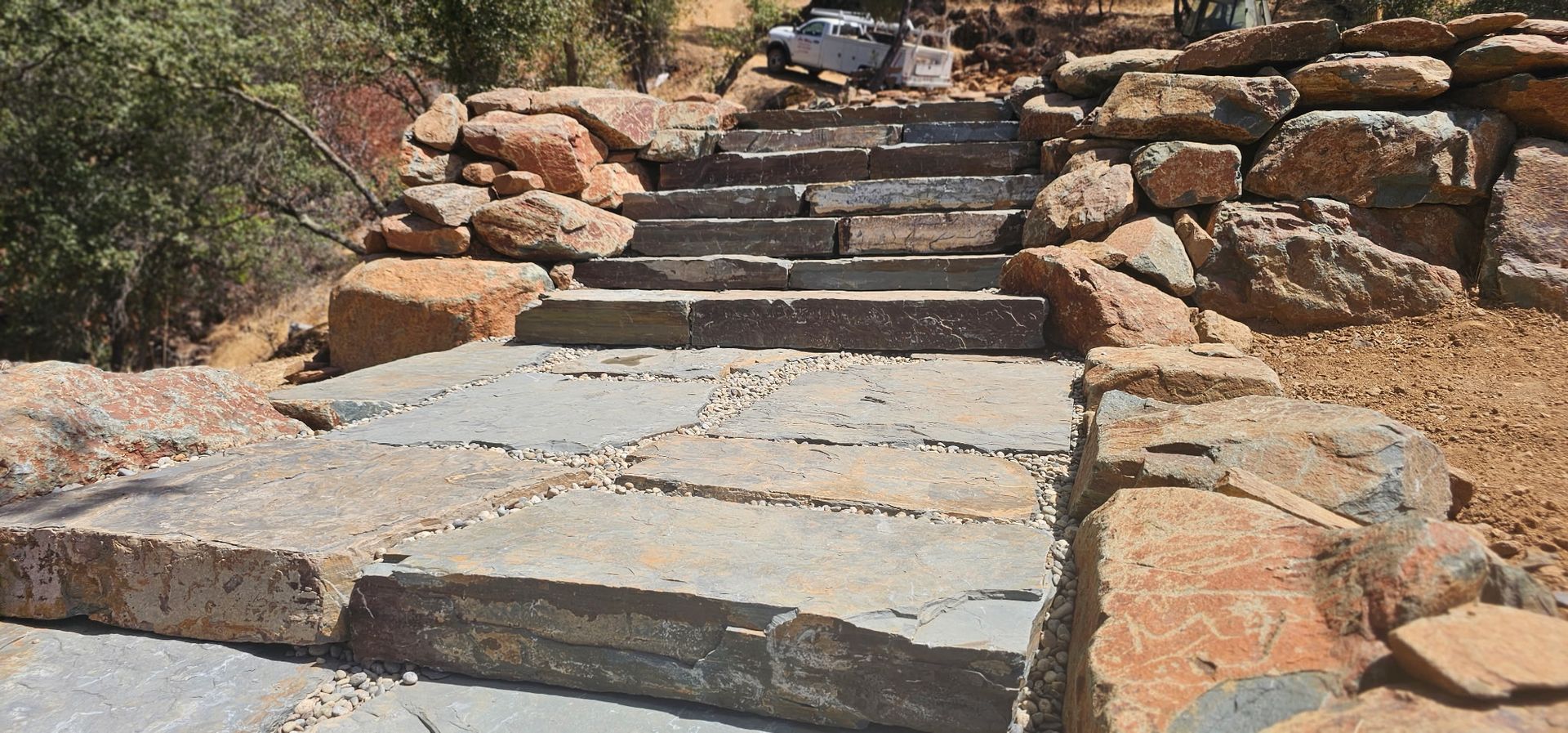 Stone steps and a walkway leading up a rocky hillside in a desert-like setting