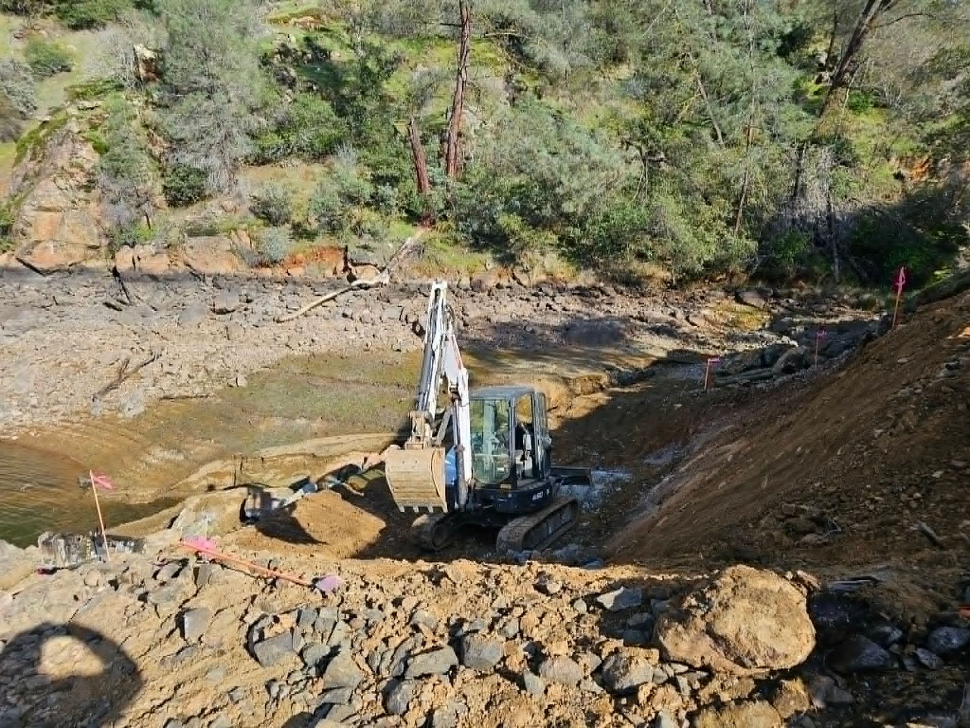 White pickup truck in a dirt field with construction equipment and trees under a blue sky