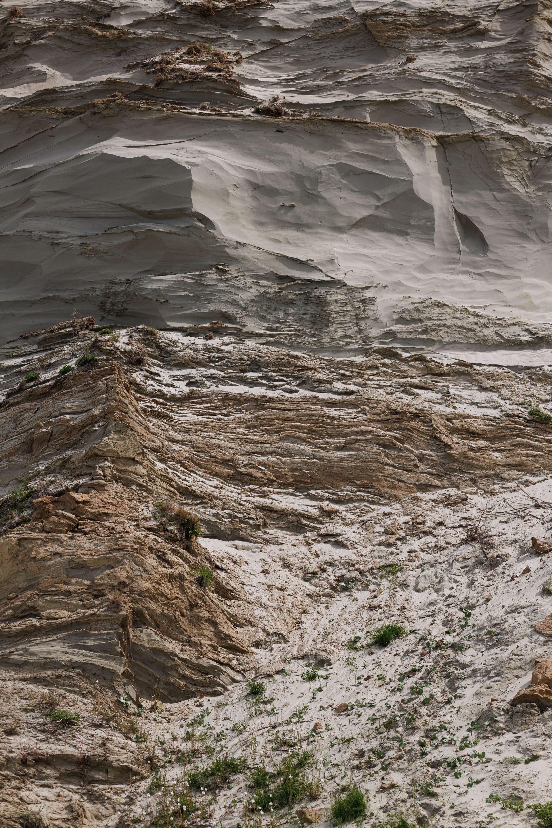 Rocky cliff face with layered stone and a snowy, icy patch near the base