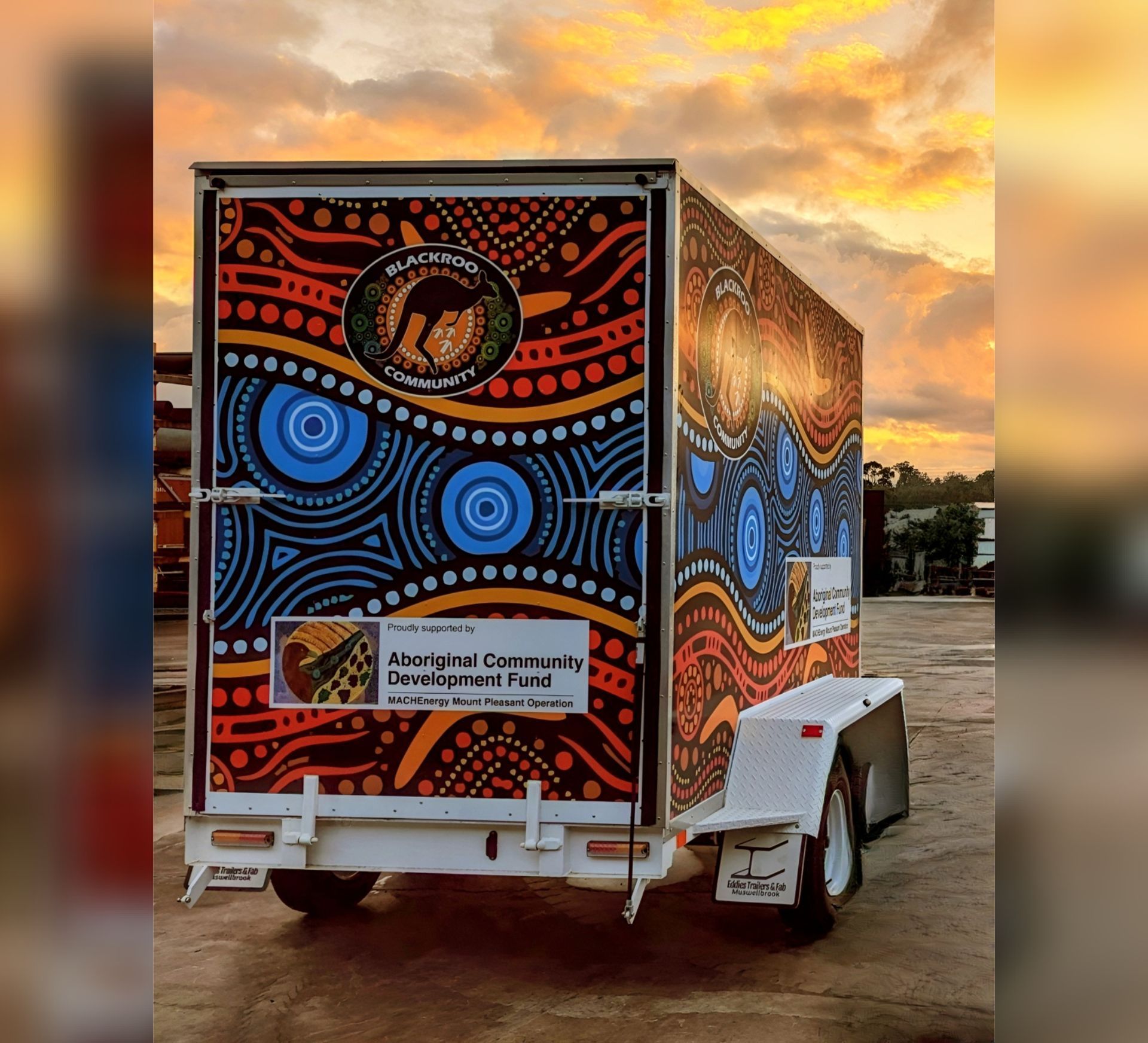 A trailer with a colourful design on it is parked in a parking lot.