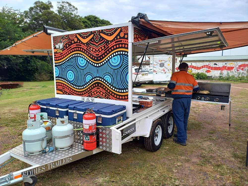 A Man Is Standing In Front Of A Trailer With A Painting On It — Eddies Trailers & Fab in Muswellbrook, NSW
