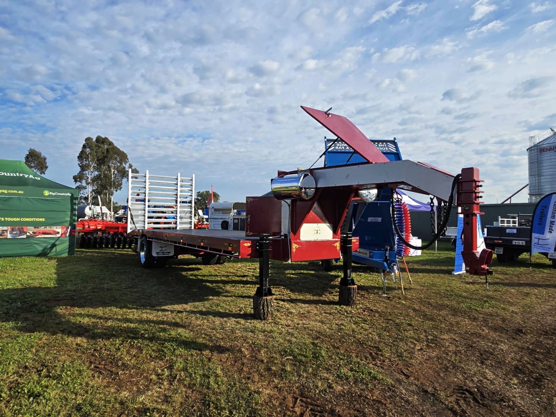 A flatbed trailer is parked in a grassy field.