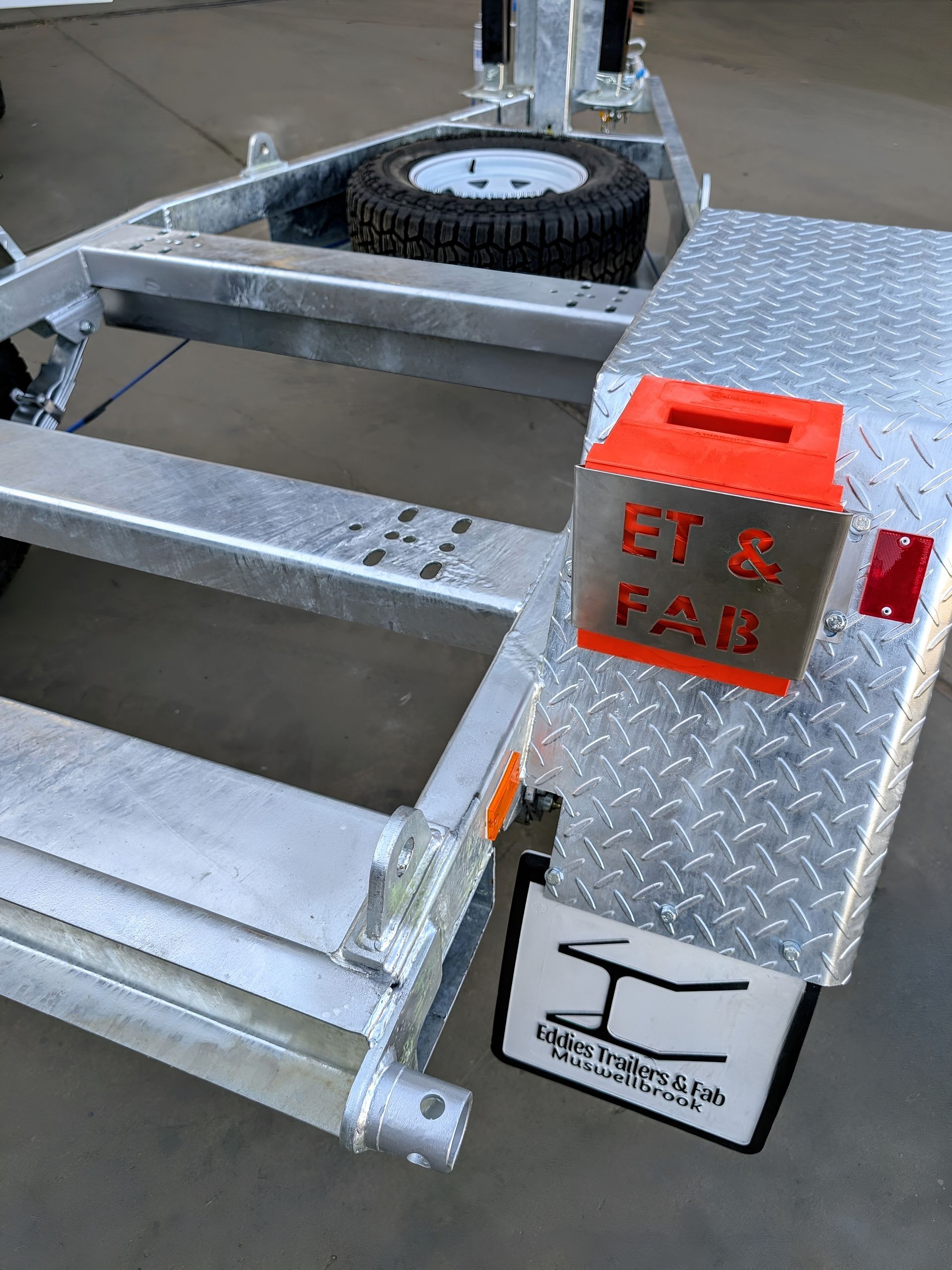 A silver trailer with an orange box that says ey & fab