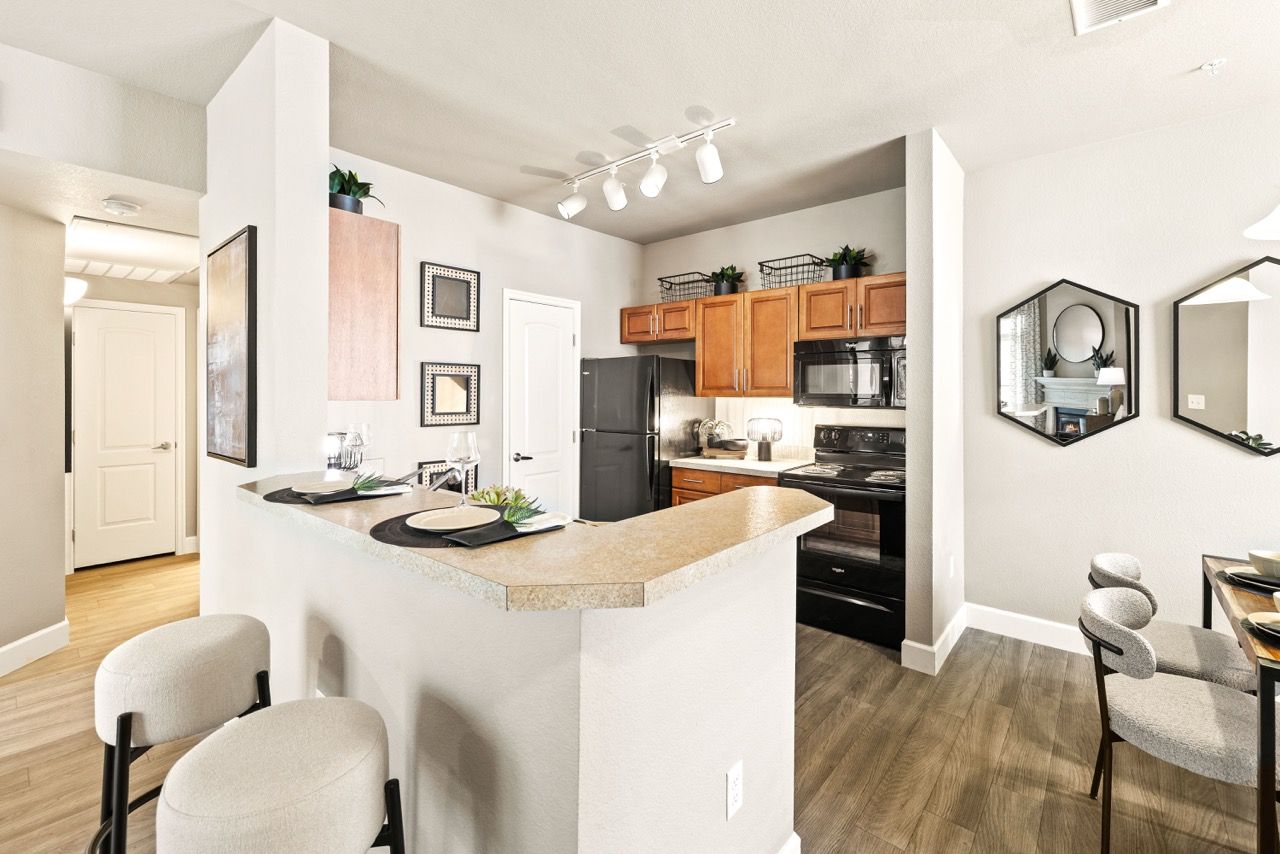 Open-concept kitchen with curved beige counter, wooden cabinets, and stainless steel appliances.