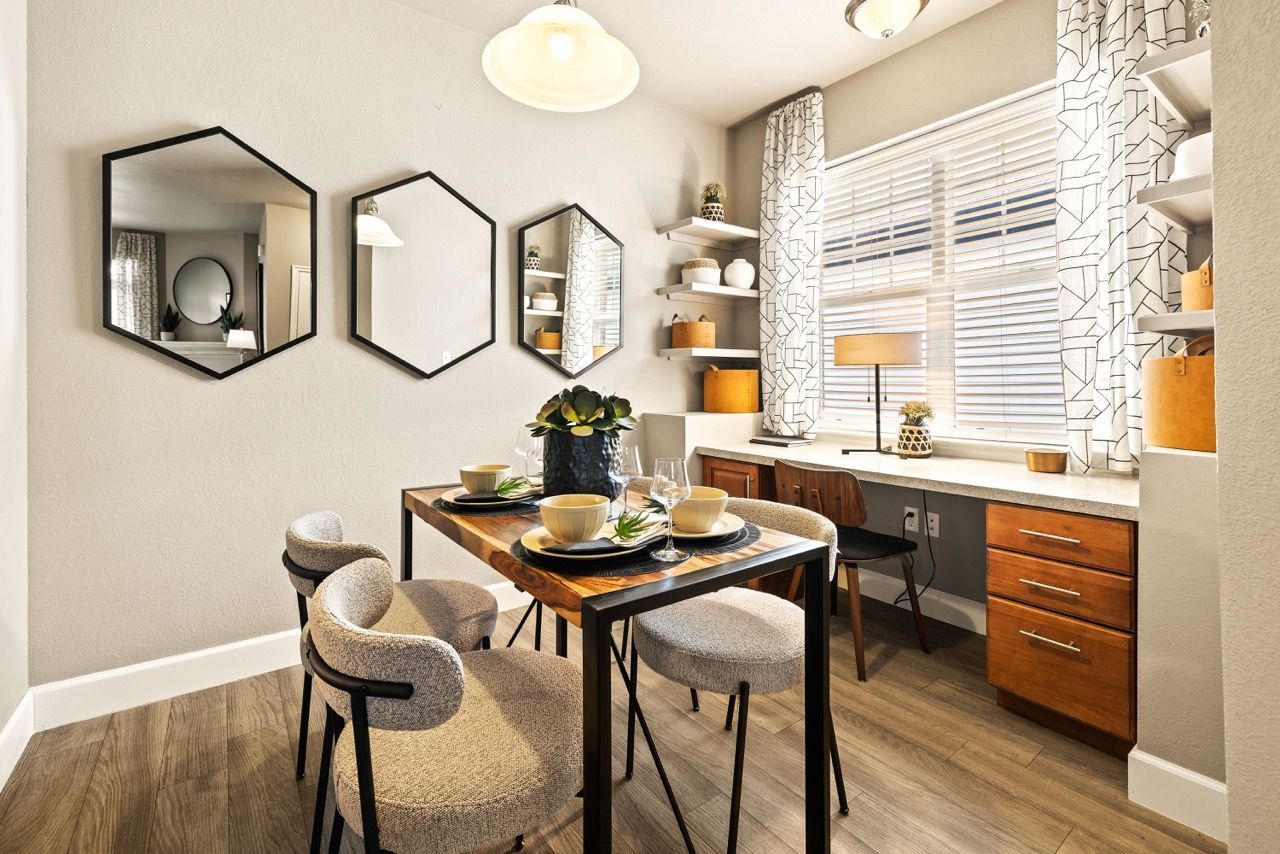 Dining area in a modern apartment with a wood table, four upholstered chairs, wall mirrors, and open shelves.