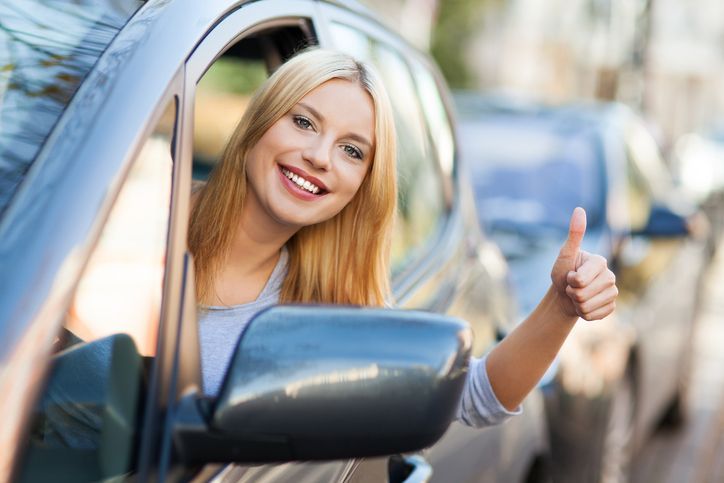 Woman in car giving thumbs up and smiling