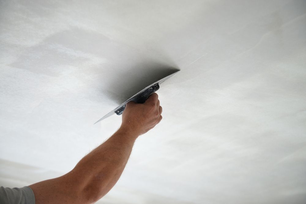 Hand Smoothing Plaster on a Ceiling With a Trowel — RAC Carpentry Services in Labrador, QLD