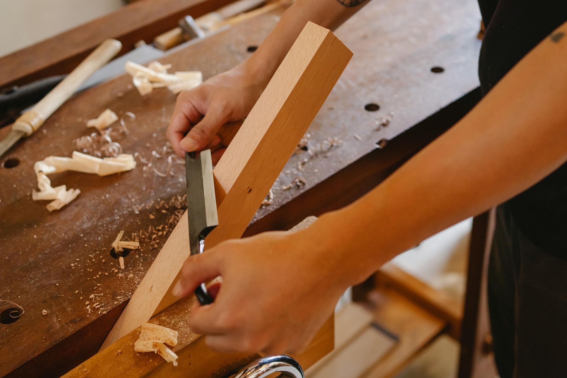 A Person Uses a Drawknife to Shave Thin Wood — RAC Carpentry Services in Oxenford, QLD