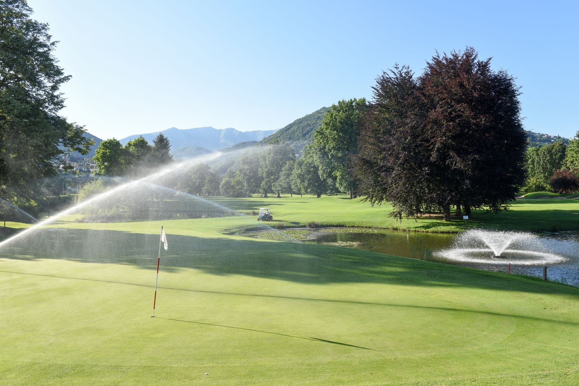 Arroseurs automatiques d'un terrain de golf arrosant un fairway verdoyant par une journée ensoleillée