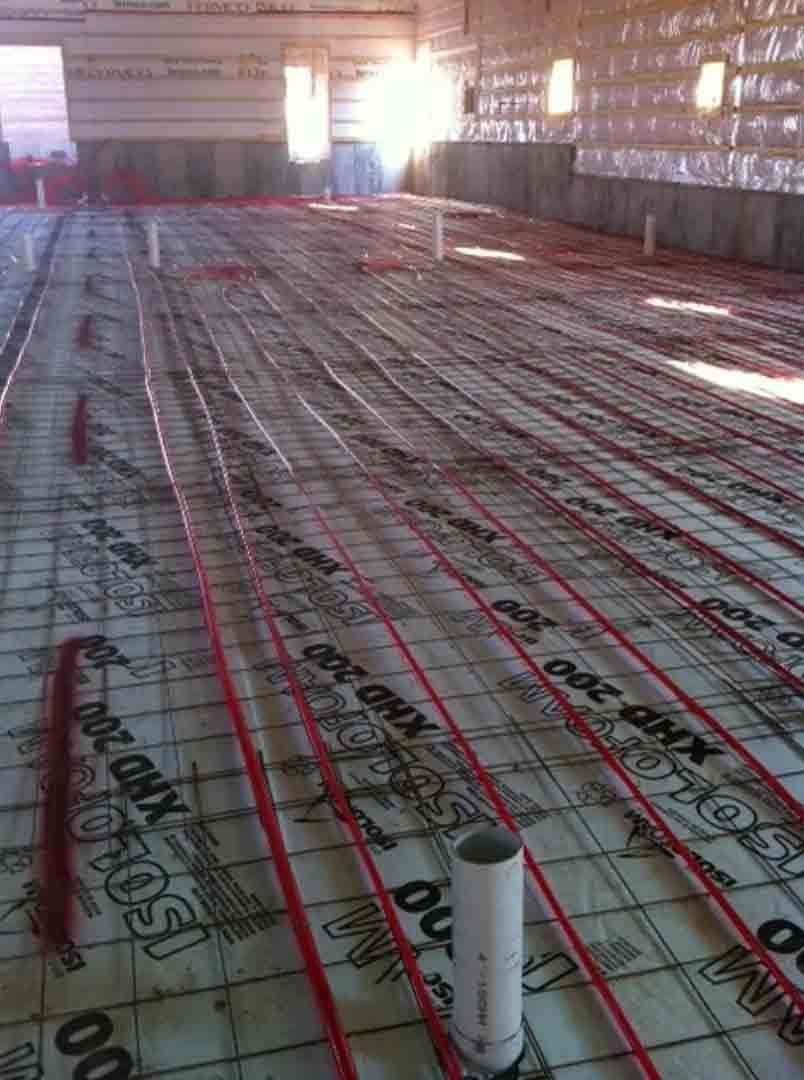 Plancher isolé en construction avec des tuyaux rouges et un tuyau blanc au premier plan