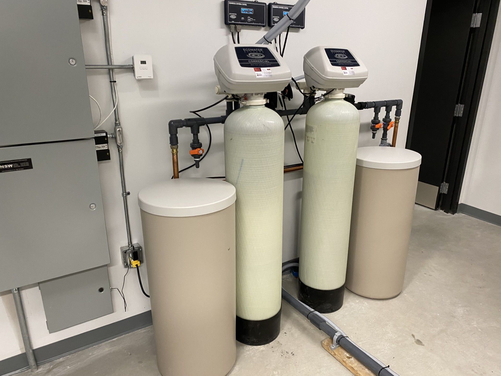 Mains installant une cartouche filtrante bleue sous un évier avec des tuyaux flexibles fixés