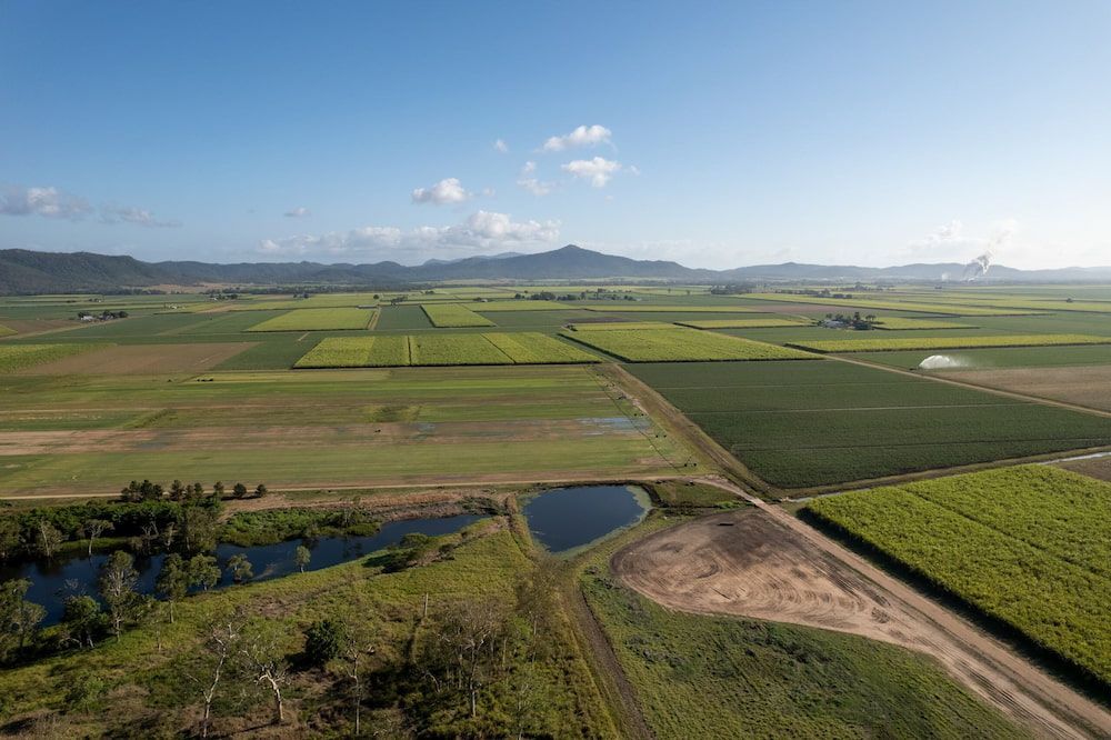 An Aerial View of a Lush Green Field With Mountains in the Background — Mr Shiny Mechanical in Marian, QLD