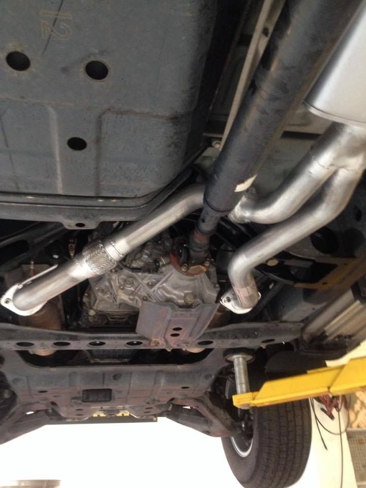 The Underside of a Car With Exhaust Pipes and a Yellow Lift — Mr Shiny Mechanical in Moranbah, QLD