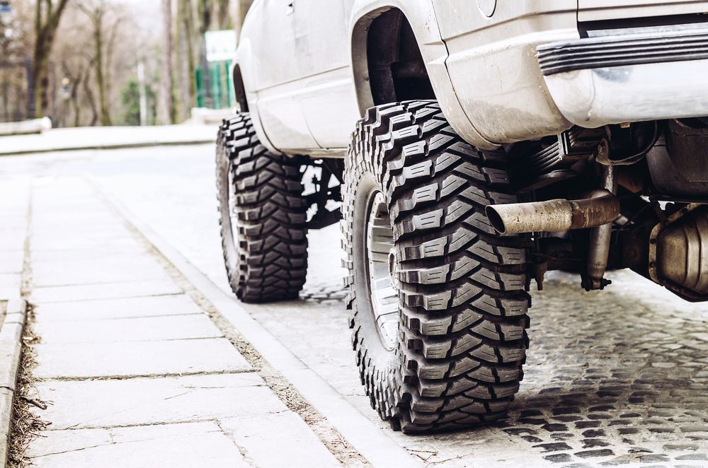 A White Truck With Big Tires is Parked on the Side of the Road — Mr Shiny Mechanical in Northern Beaches, QLD