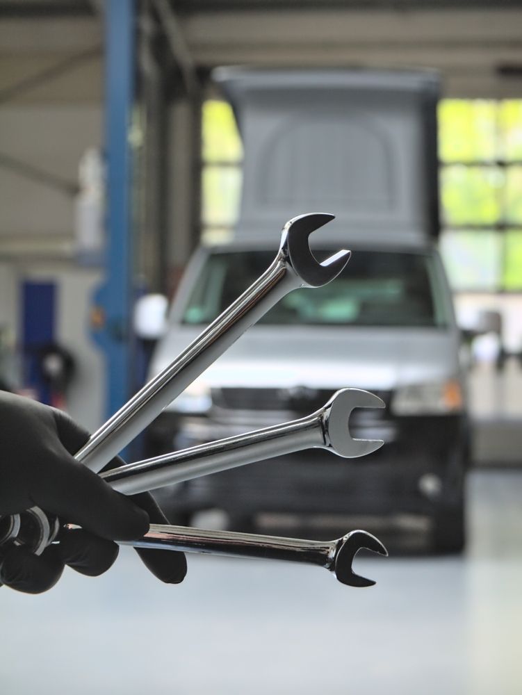 A Person is Holding a Bunch of Wrenches in Front of a Car — Mr Shiny Mechanical in Northern Beaches, QLD