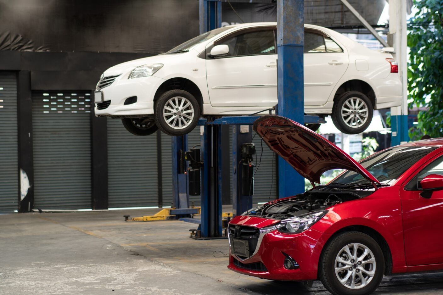 Two Cars Are Sitting on a Lift in a Garage — Mr Shiny Mechanical in Northern Beaches, QLD