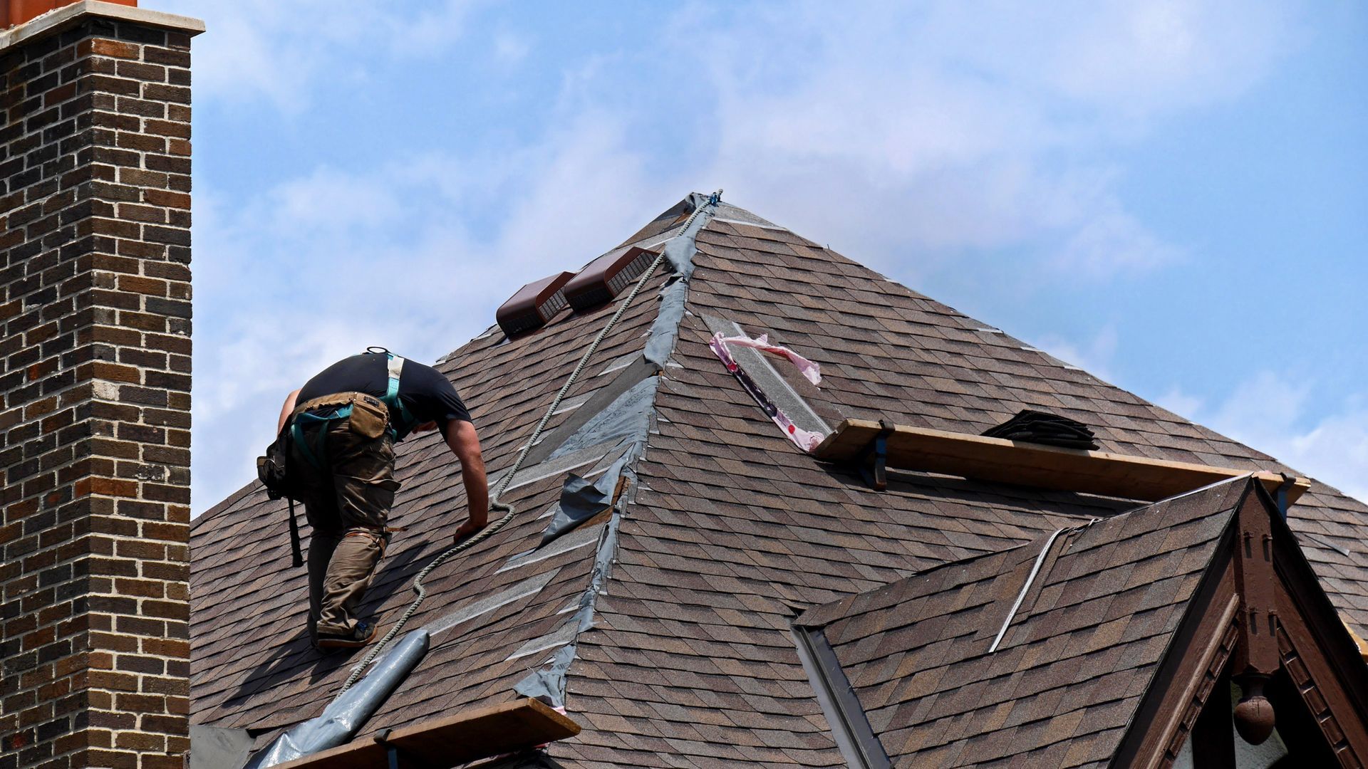 A man is working on the roof of a house.