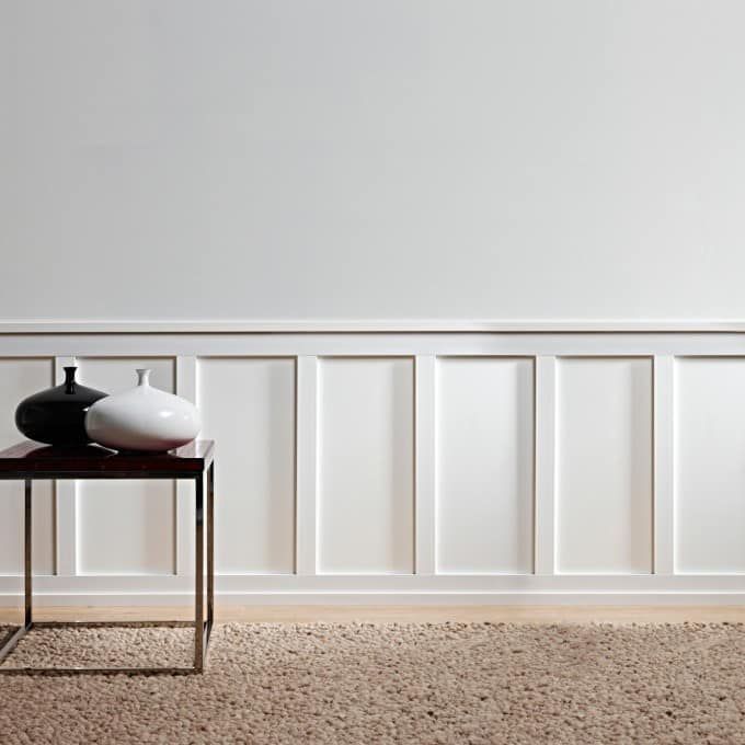 Due vasi sono appoggiati su un tavolo davanti a un muro bianco.