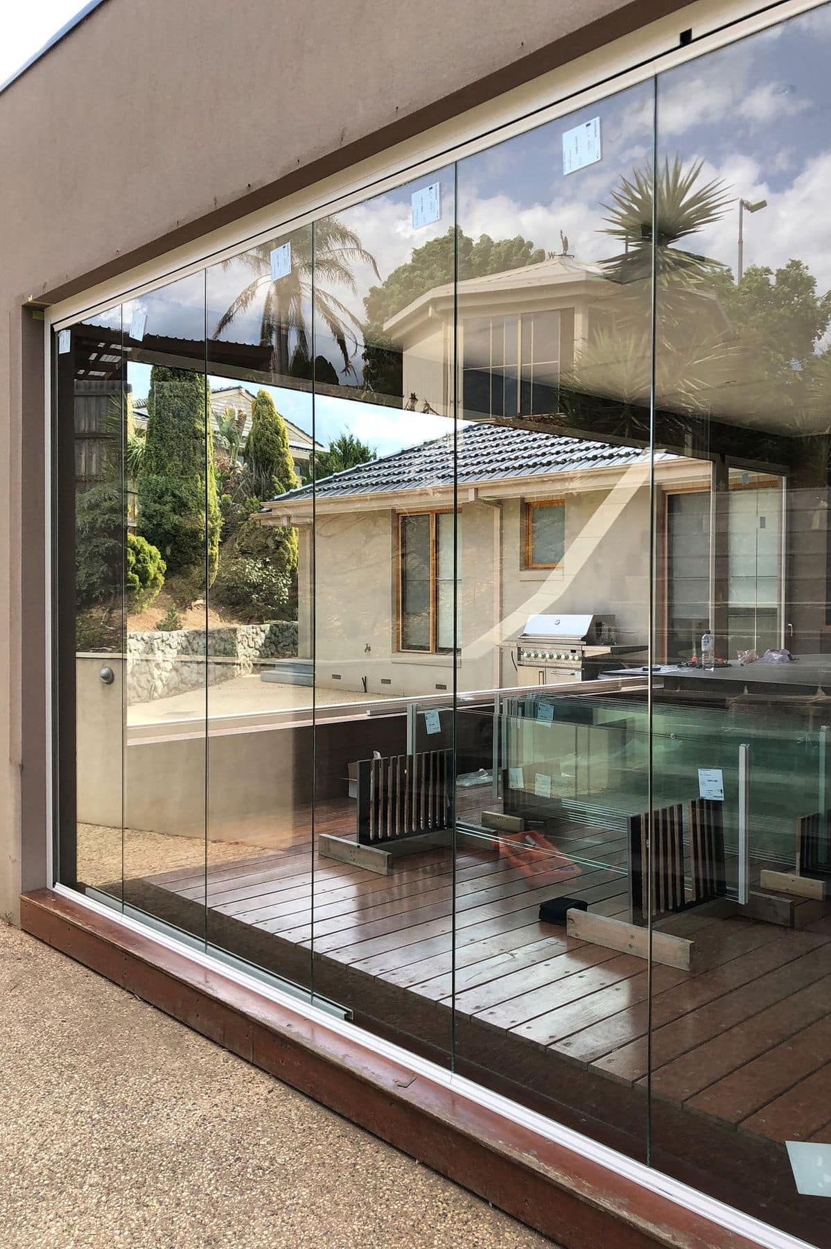 Una parete di vetro su cui è riflessa una casa.