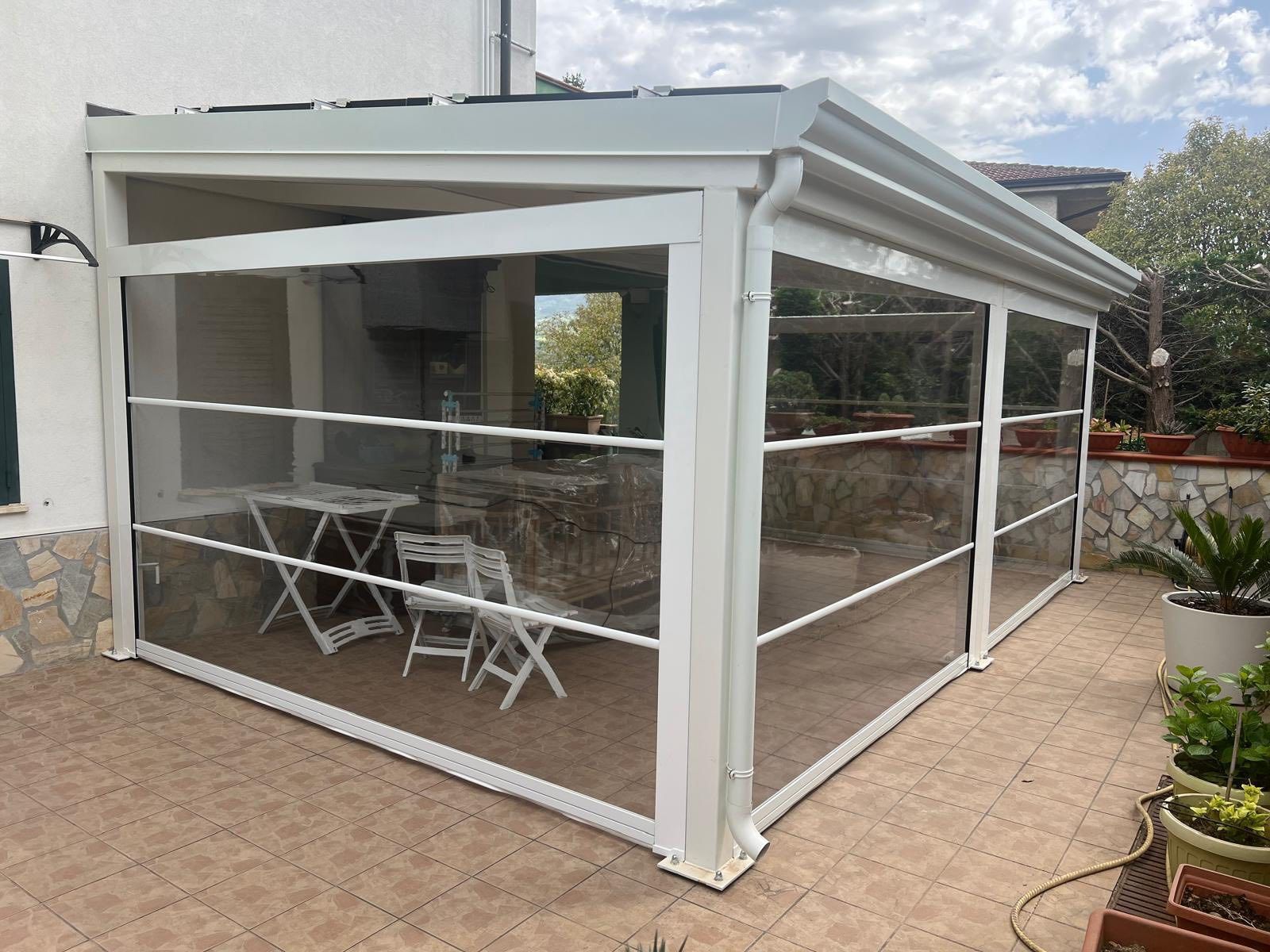 Un pergolato bianco con tavoli e sedie su un patio.