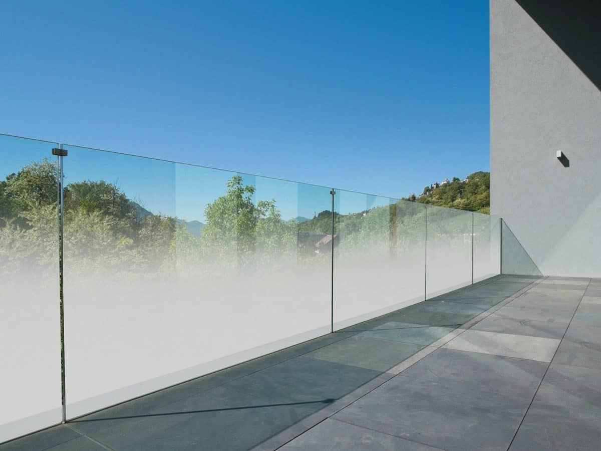 Un balcone con una ringhiera in vetro e un cielo azzurro sullo sfondo