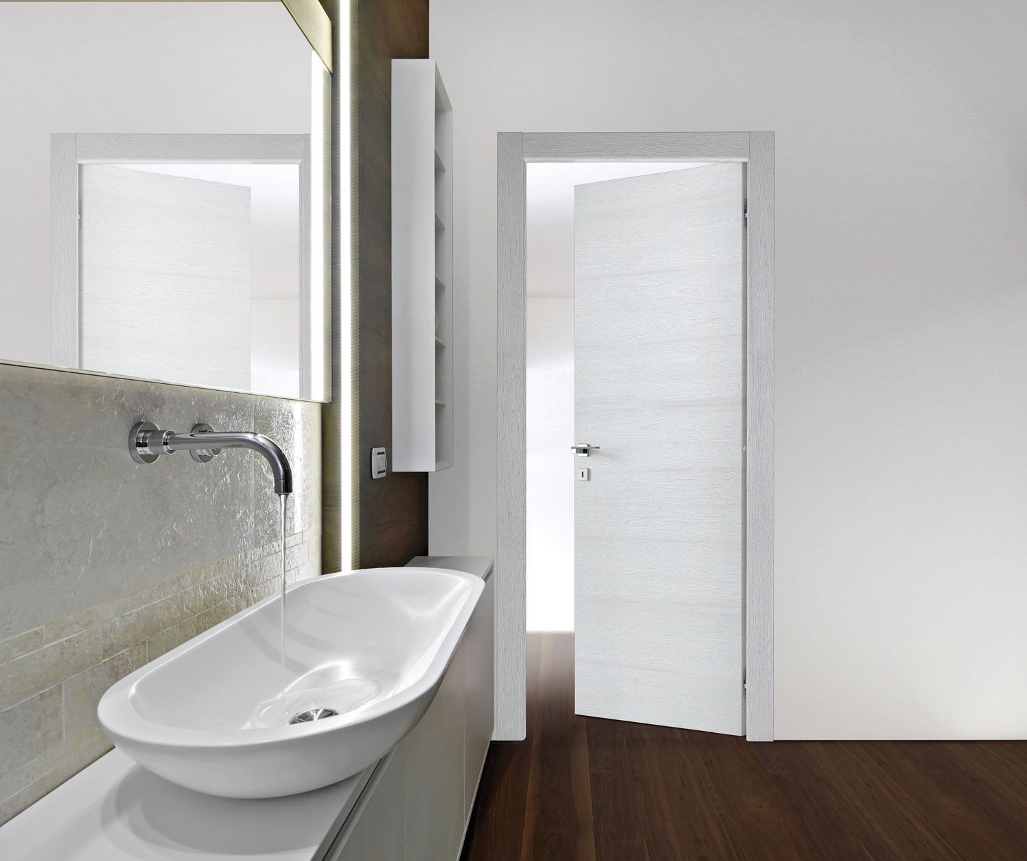 Bagno moderno con lavabo, specchio, pavimento in legno e porta che si apre su una luminosa stanza adiacente.