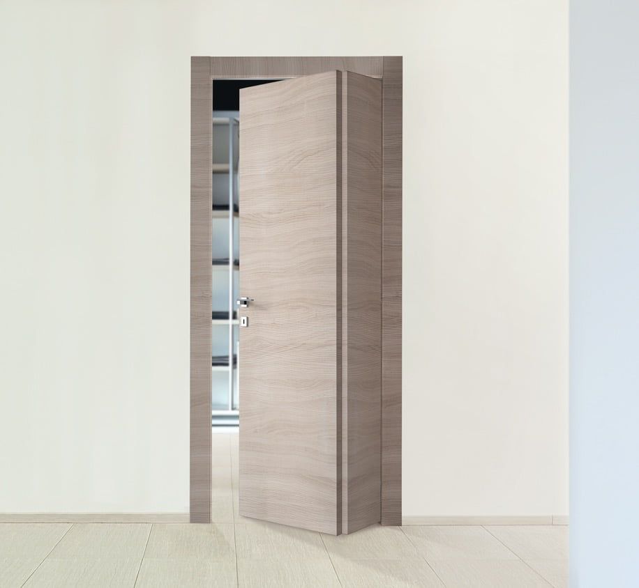 Porta in legno chiaro parzialmente aperta in una stanza dagli interni minimalisti.