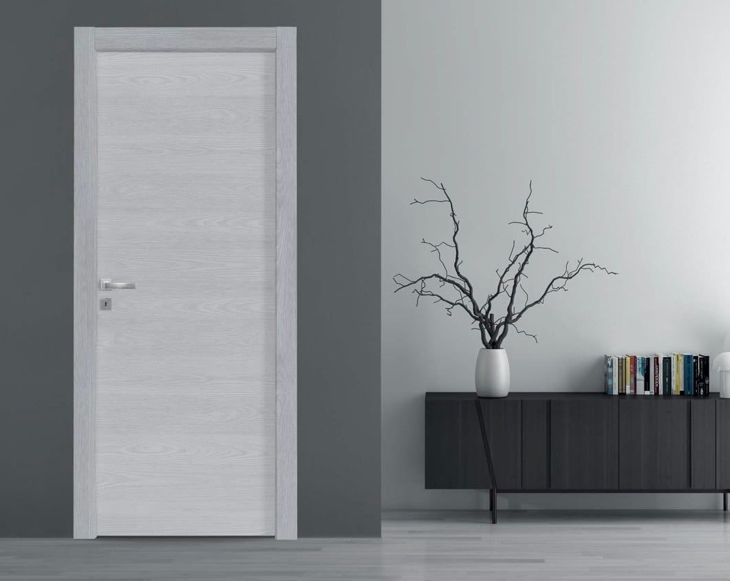 Interno moderno con porta bianca, parete d'accento scura e credenza nera con vaso e libri.