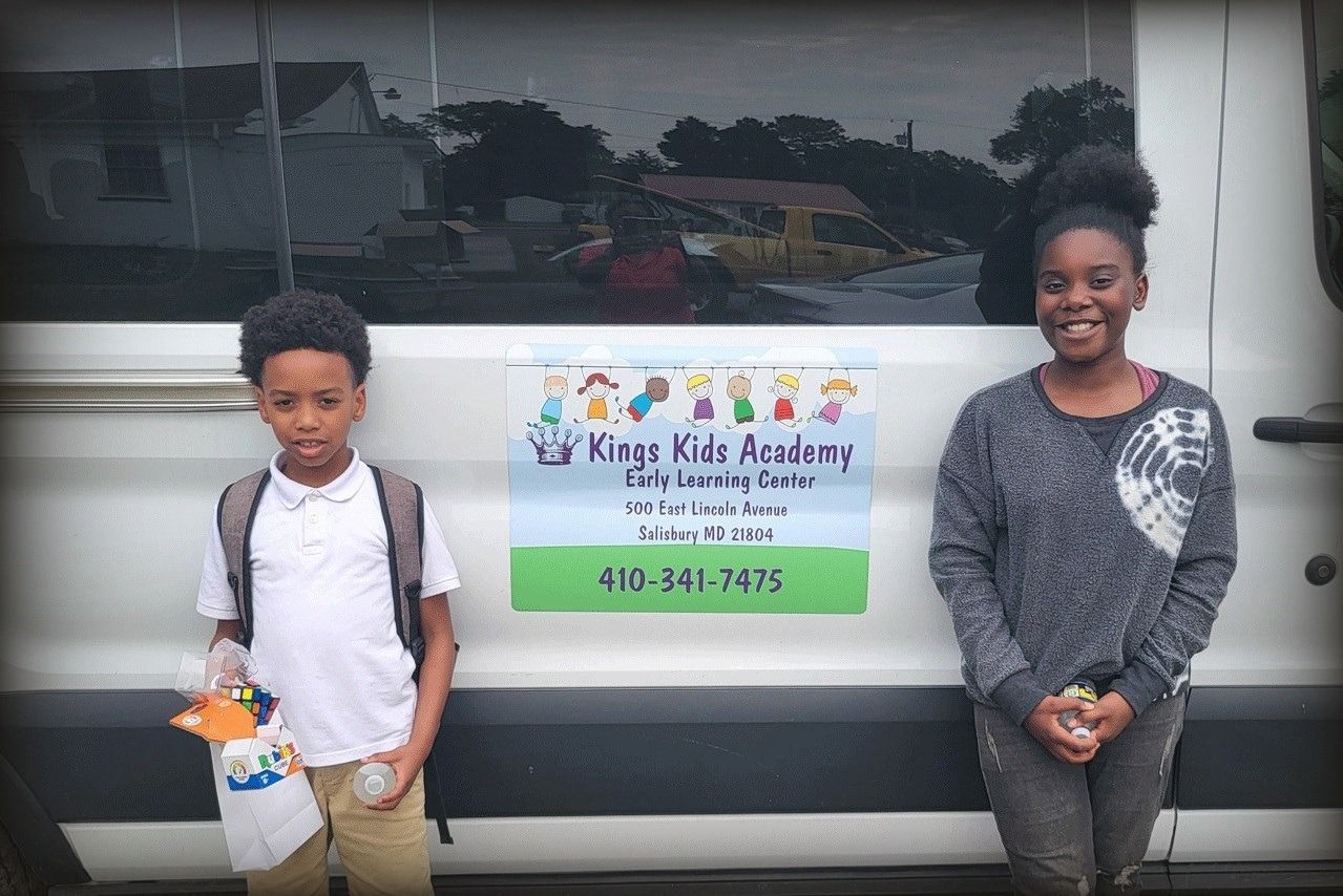 Two kids standing in front of a van with 