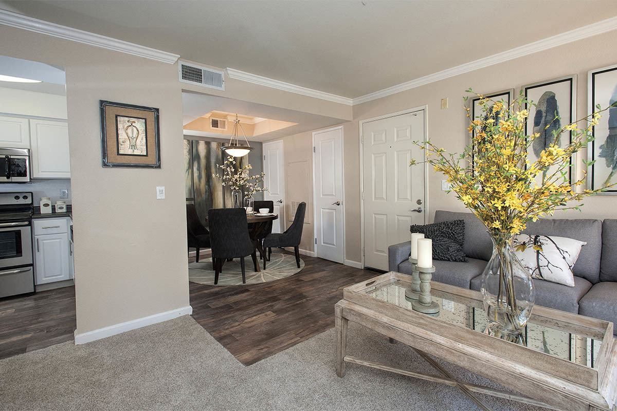 Open-concept living area with a gray sofa, glass coffee table, and dining table in an apartment at Marina's Edge.