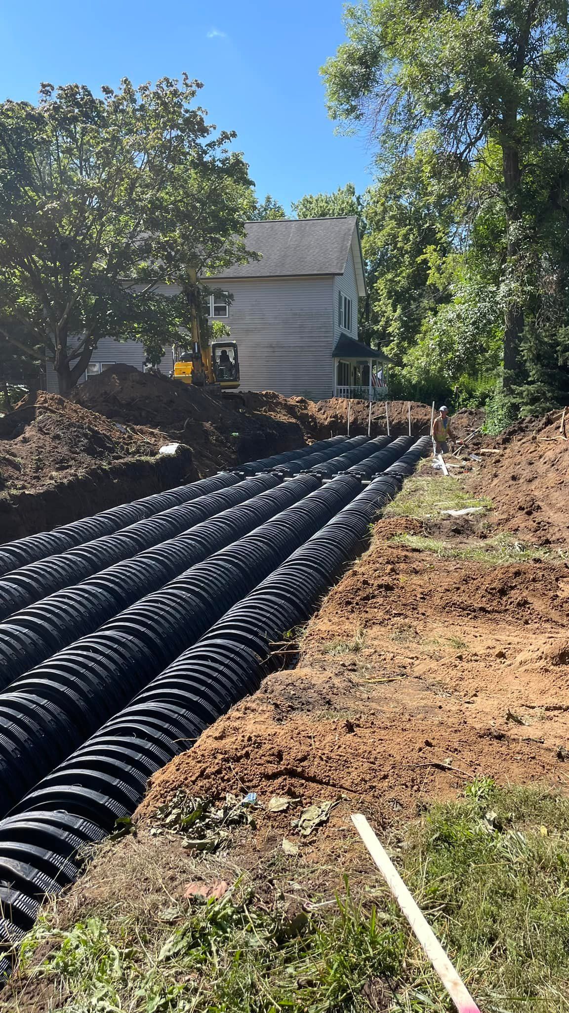 A septic system is being installed in a yard in front of a house.