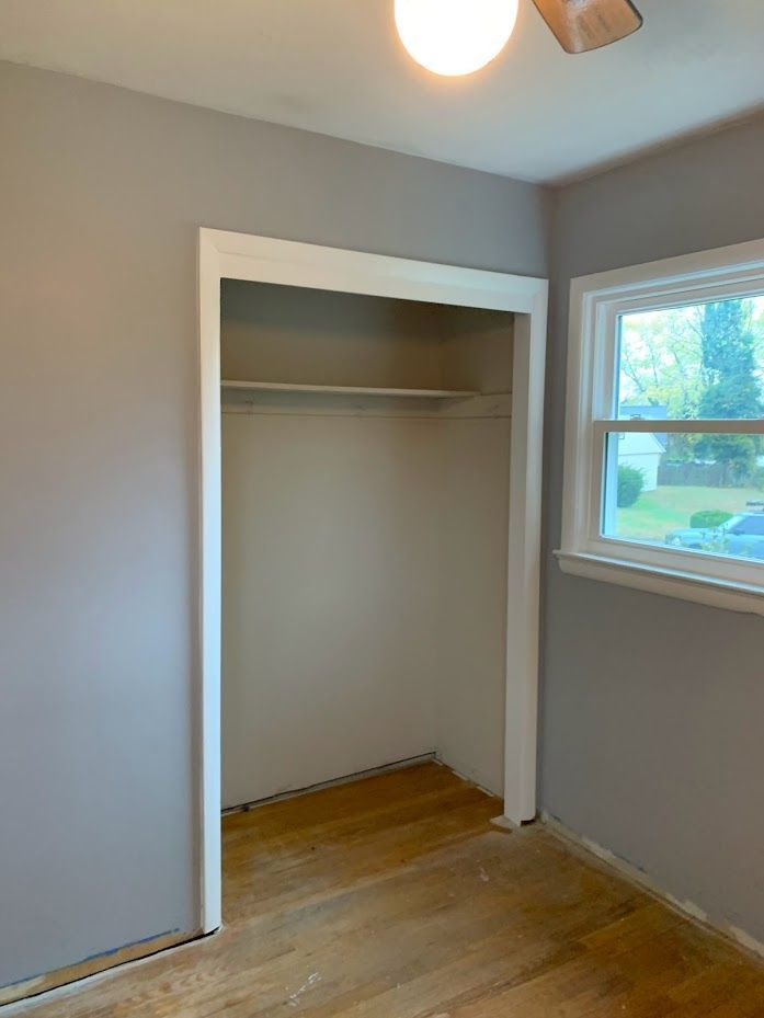 An empty room with a closet and a window.