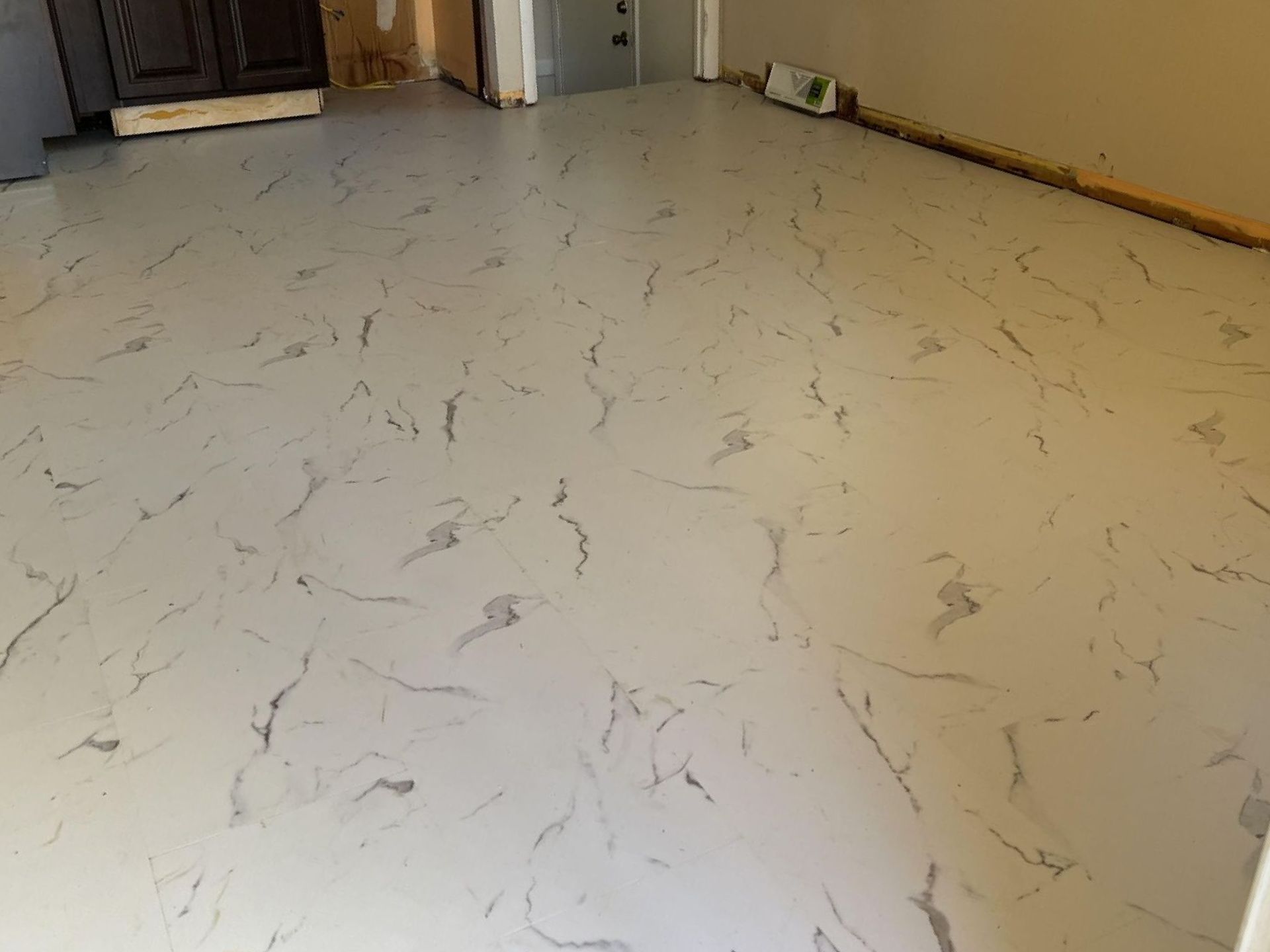 A white floor with a marble pattern is being installed in a room.