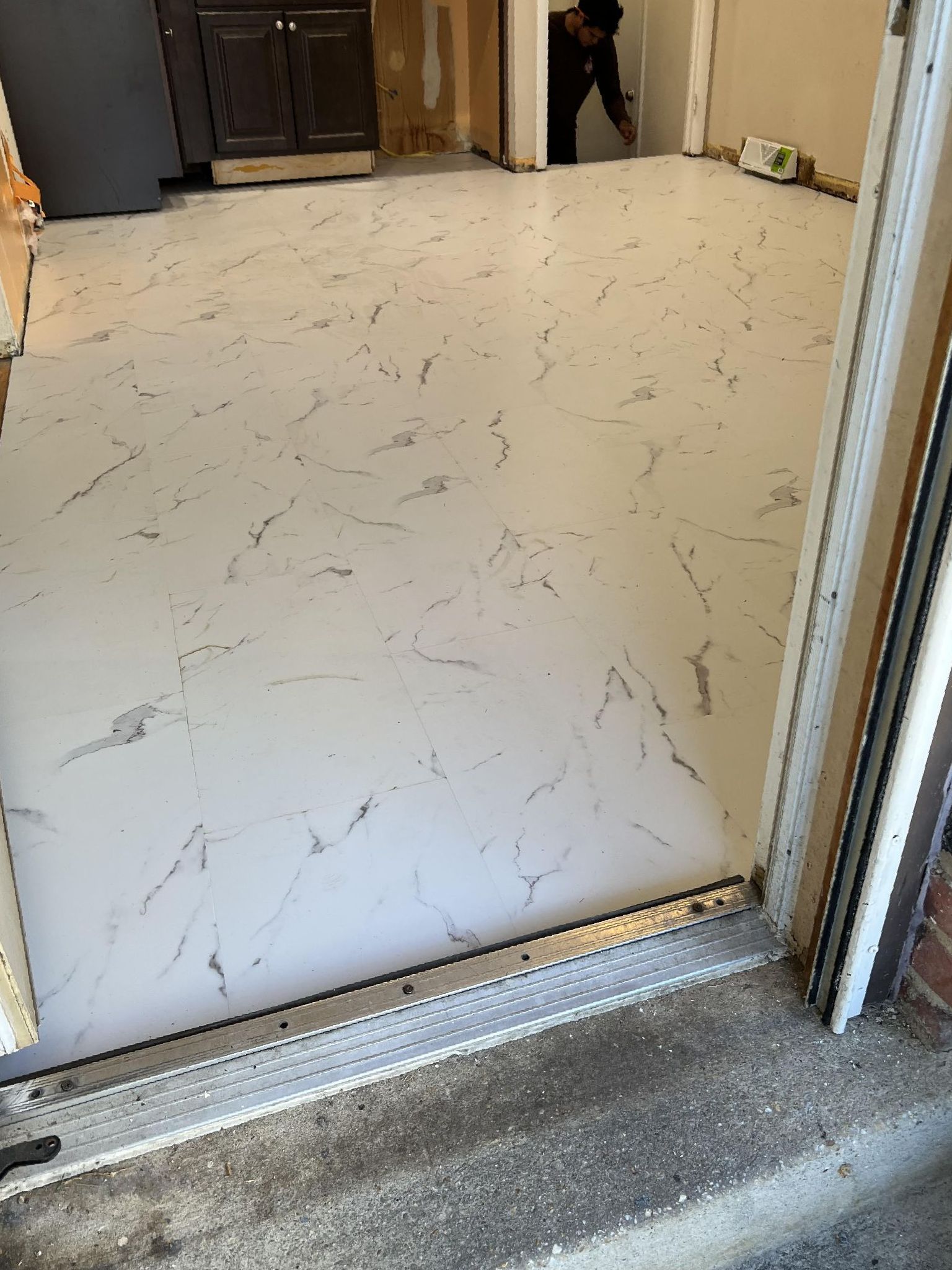 A white marble floor is being installed in a kitchen.