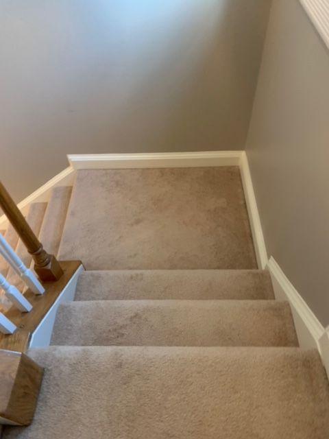 A staircase with a carpeted floor and a wooden railing.