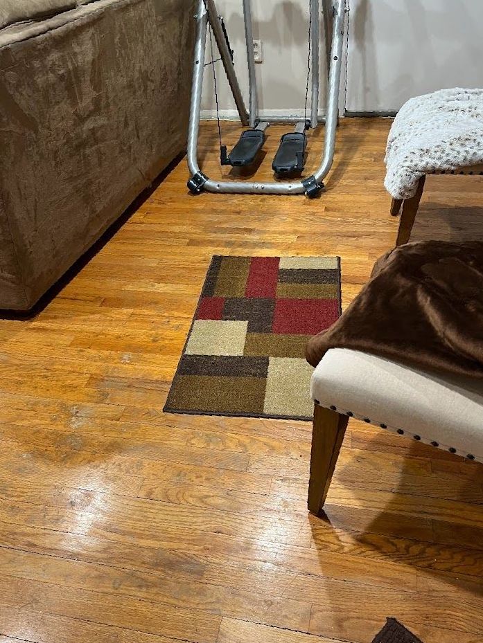 A living room with hardwood floors and a rug on the floor.