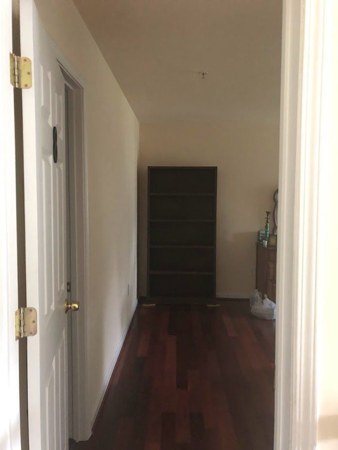 A hallway with hardwood floors and a dresser in the middle of it.