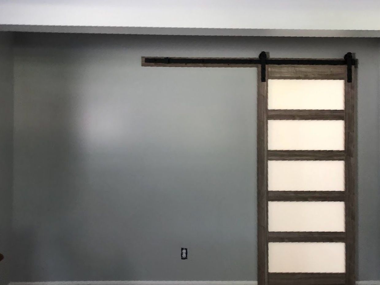 A sliding barn door is hanging on a wall in a room.