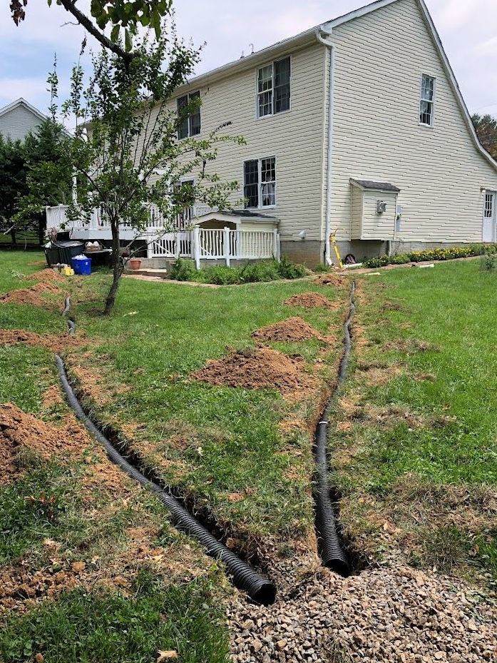 A house with a drain pipe in the grass in front of it.