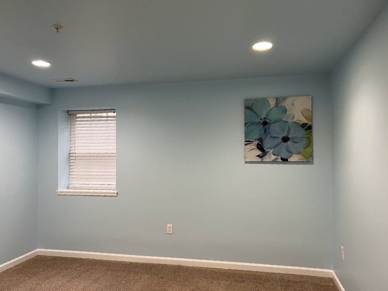 A room with blue walls and a painting on the wall.