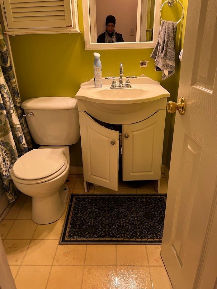 A bathroom with a toilet , sink and mirror