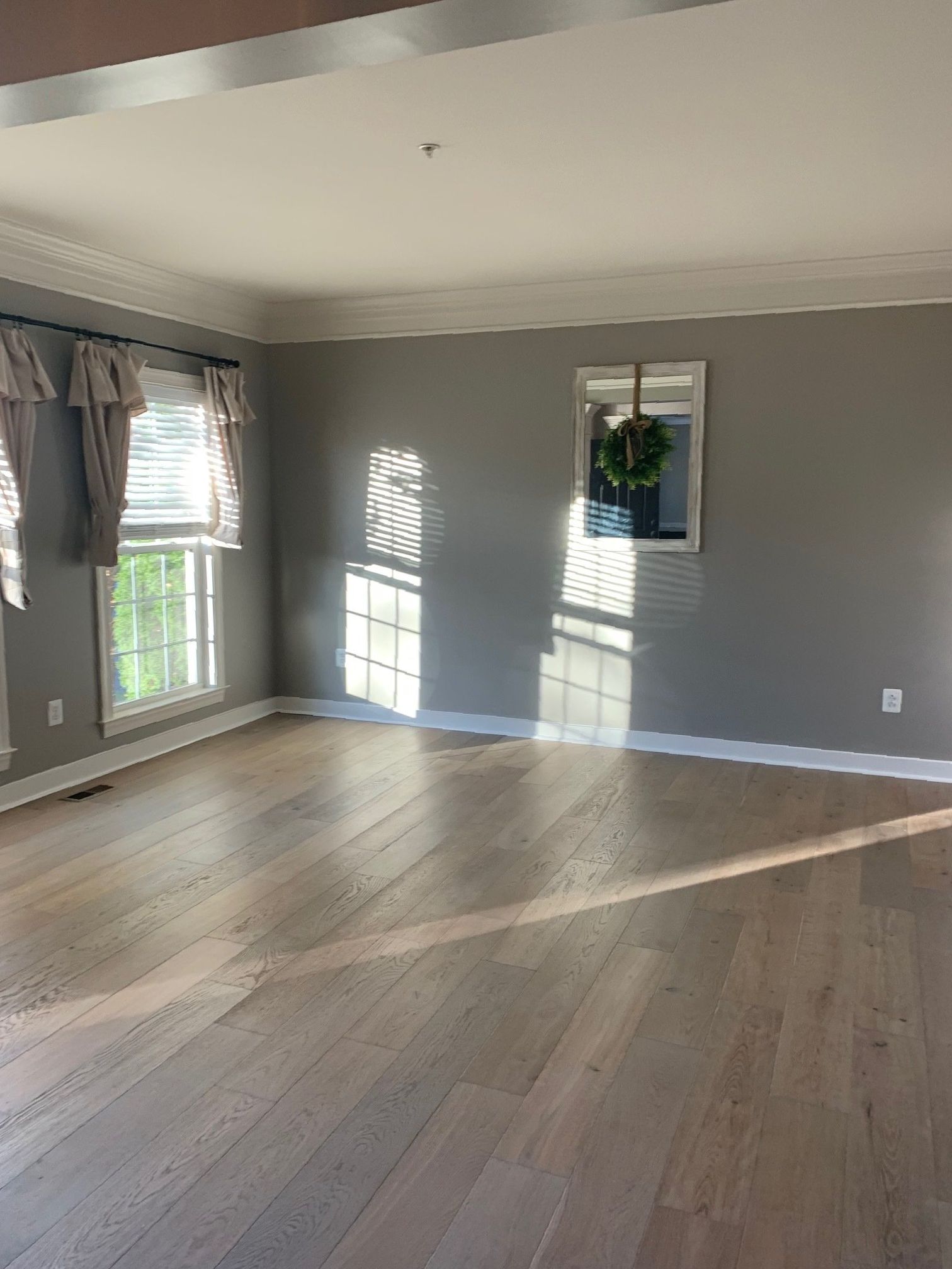 An empty living room with hardwood floors and gray walls.