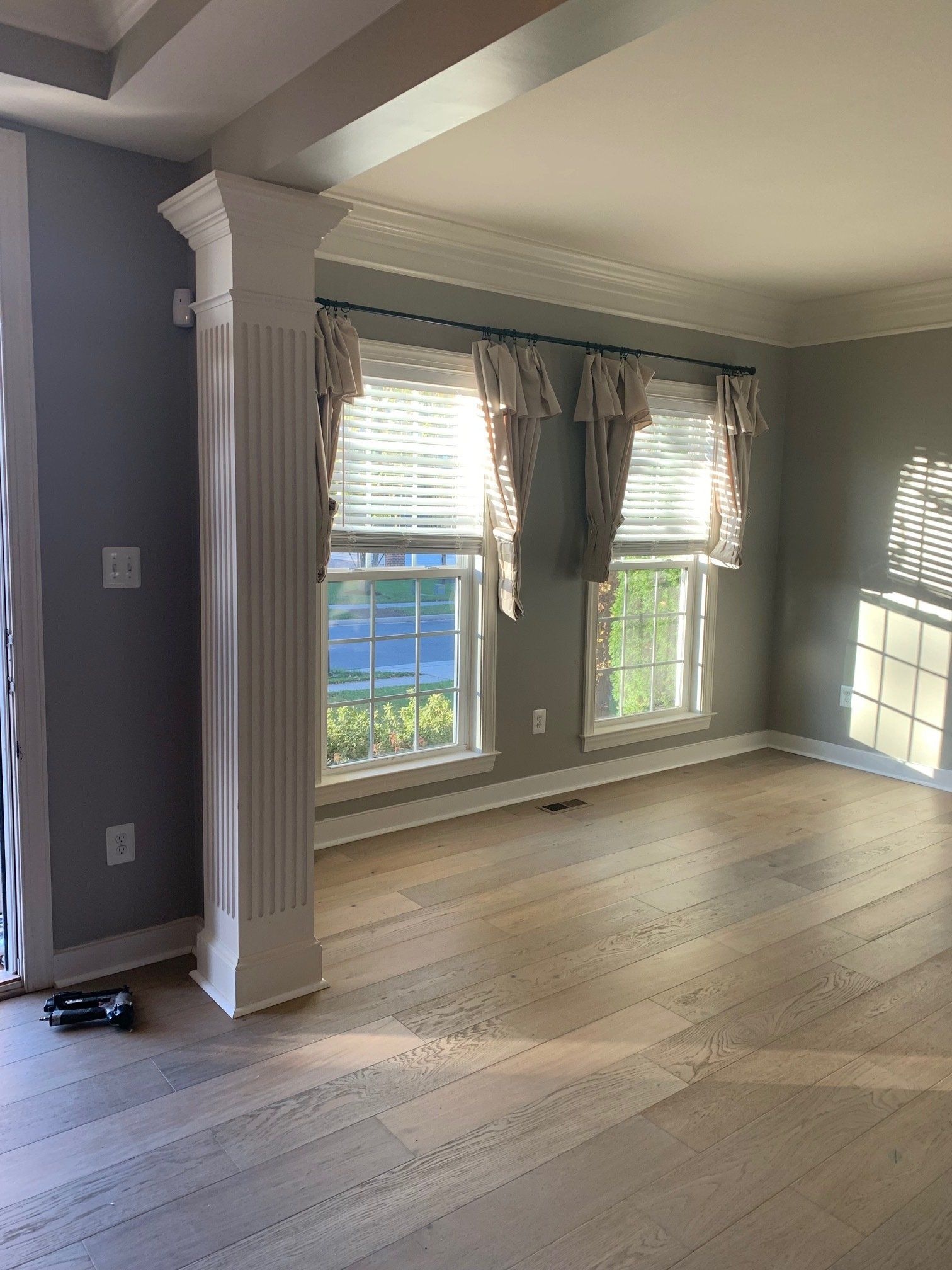 An empty living room with hardwood floors and a white column.