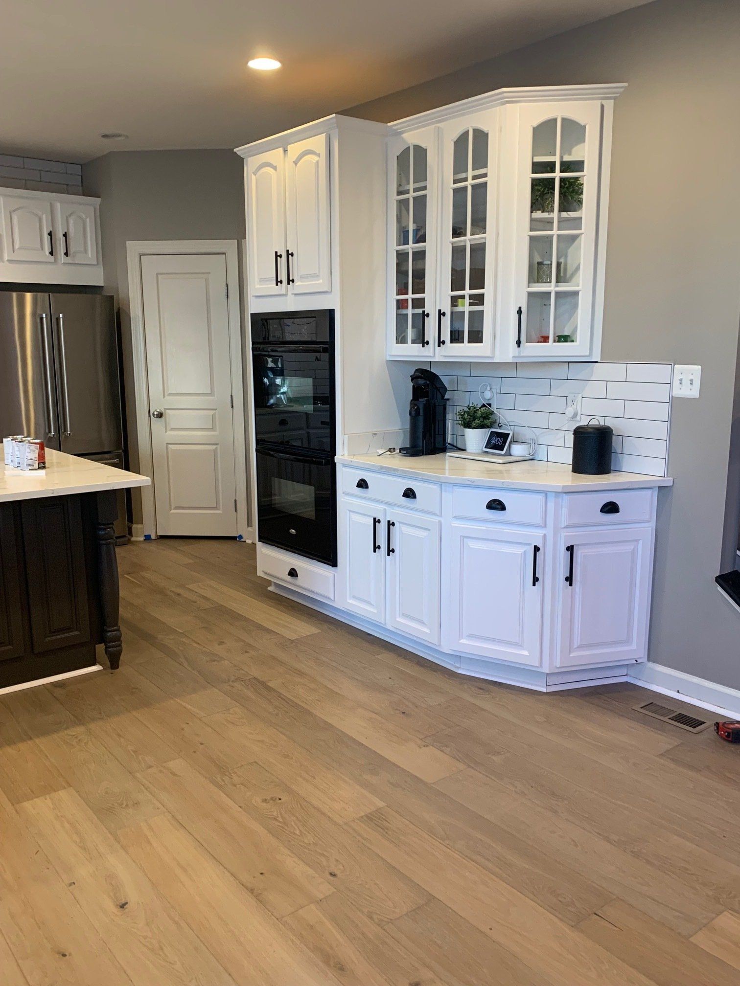 A kitchen with white cabinets , stainless steel appliances , and hardwood floors.
