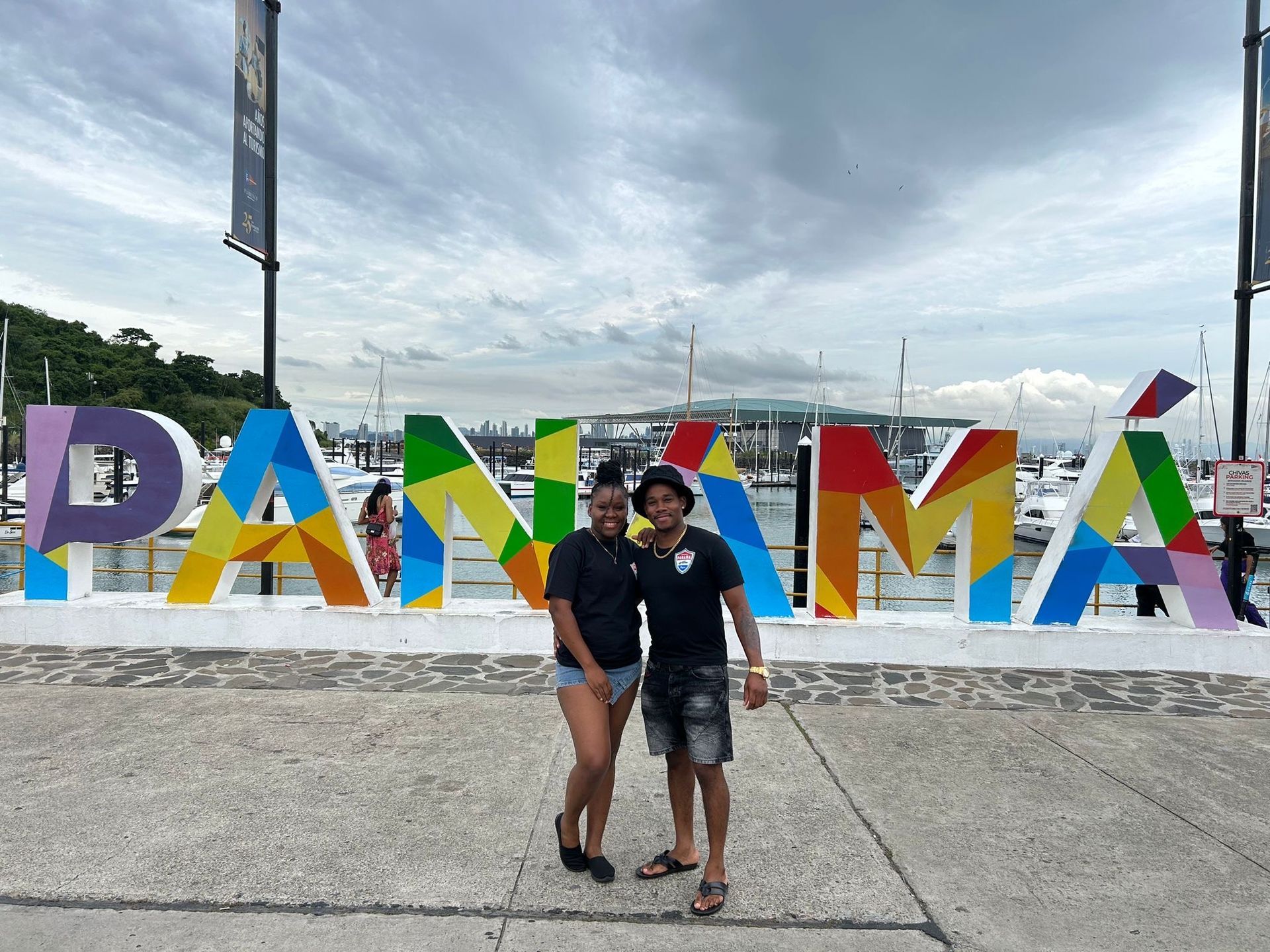 Two people stand smiling in front of a colorful, multi-patterned 
