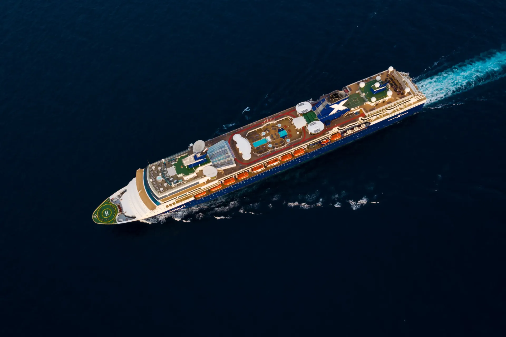A large cruise ship traveling towards the horizon with clouds seen in the distance