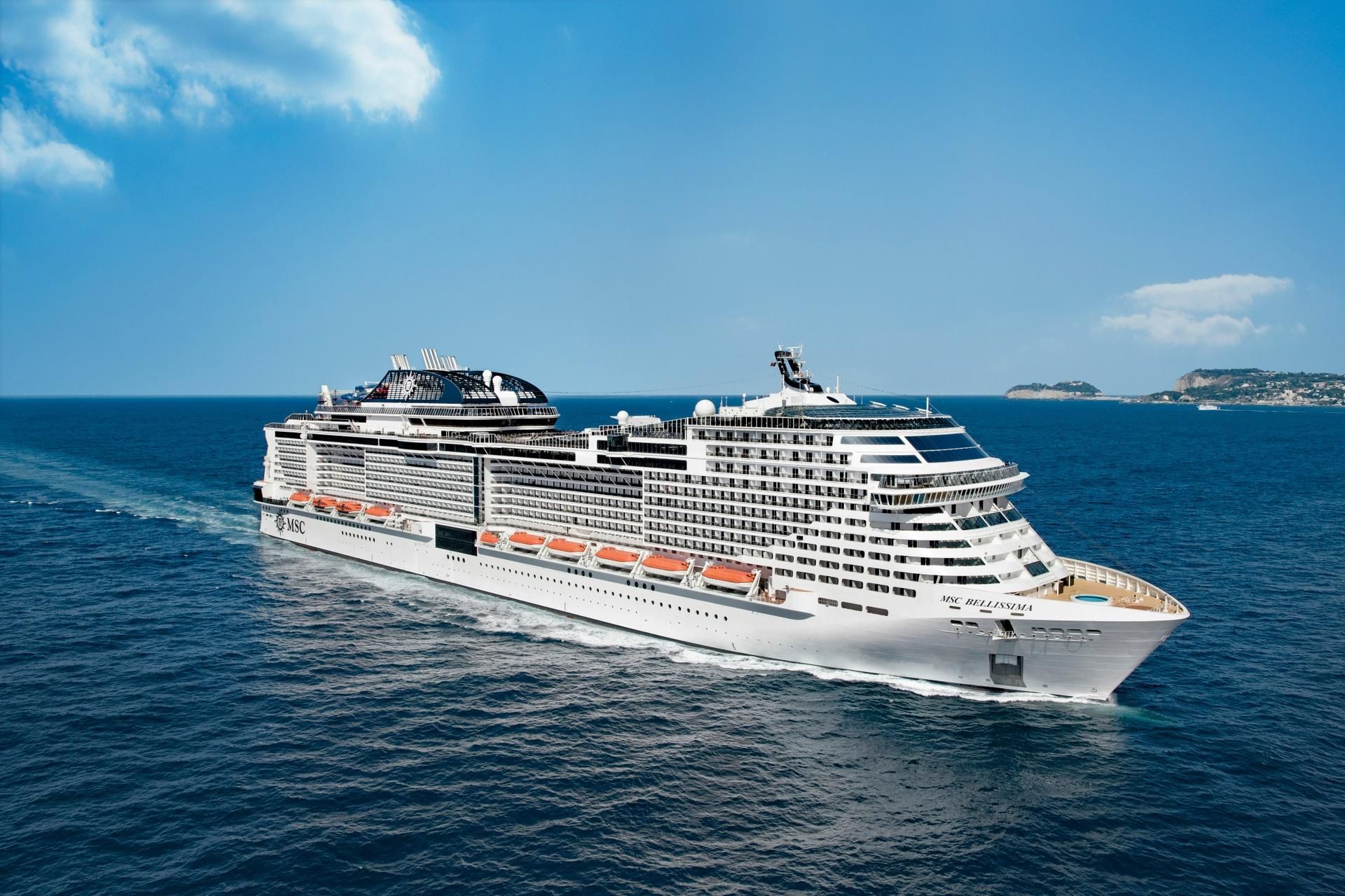 A large cruise ship traveling towards the horizon with clouds seen in the distance