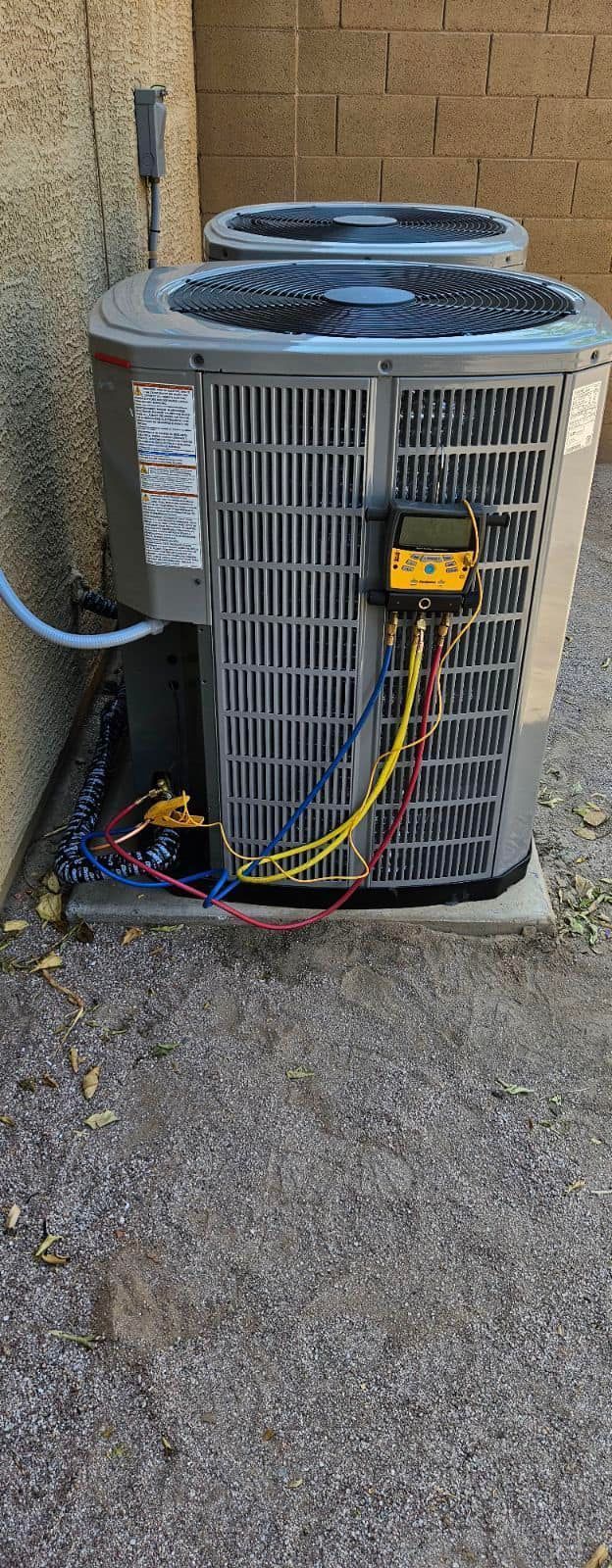 Outdoor air conditioning unit with exposed wires beside a brick wall