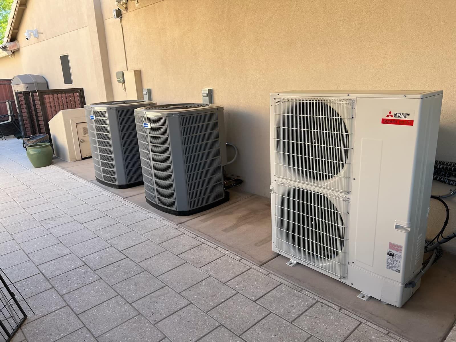 Outdoor row of HVAC units and air conditioners beside a beige building wall