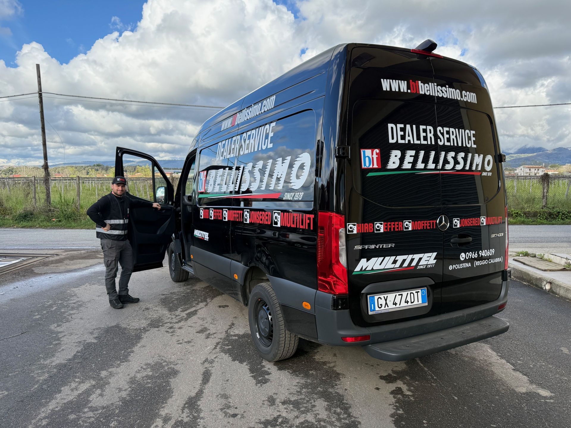A man is standing next to a black van on the side of the road.